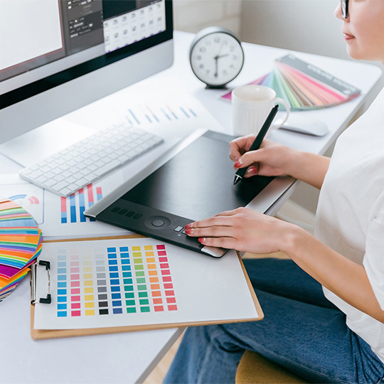 株式会社SORAQのデザイナーが色見本とタブレットでホームページ制作のデザインを作成している