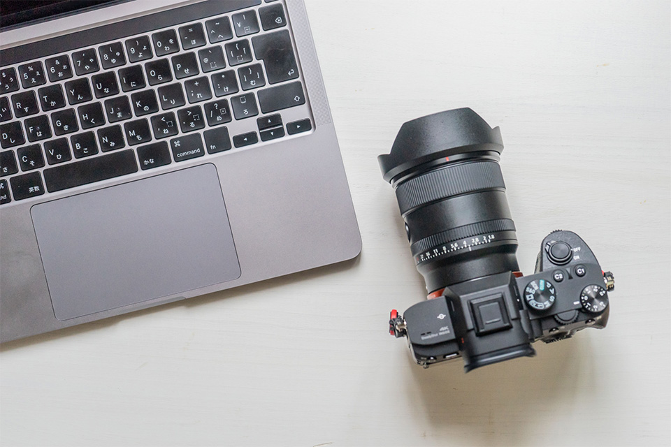 株式会社SORAQの撮影用カメラとノートPCが並ぶウェブマーケティング・ホームページ制作・運用会社の作業机風景