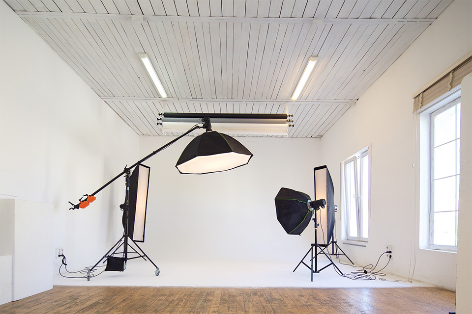 株式会社SORAQの白い撮影スタジオで商品撮影用のライティング機材が設置されている