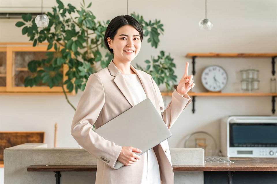 株式会社SORAQの女性担当者がラップトップを持ちホームページ制作の提案を説明している